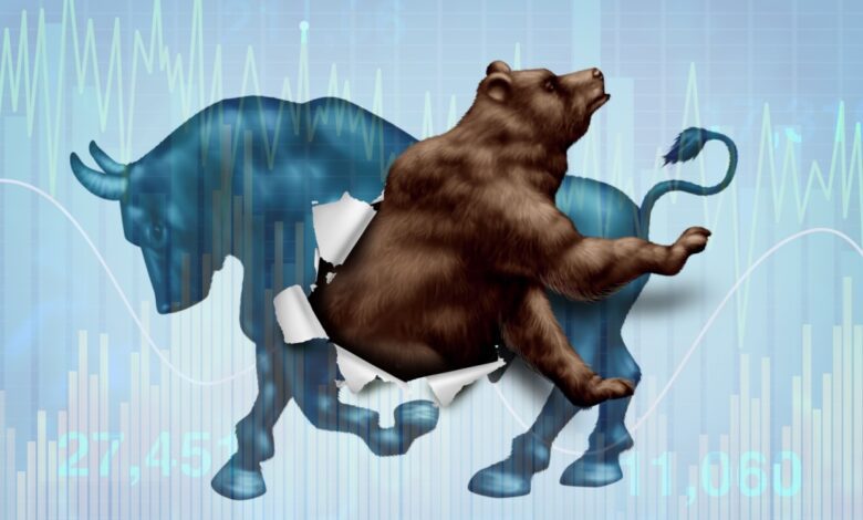 A bear bursts through the body of a bull, symbolizing a shift from a bull market to a bear market, with financial charts in the background.