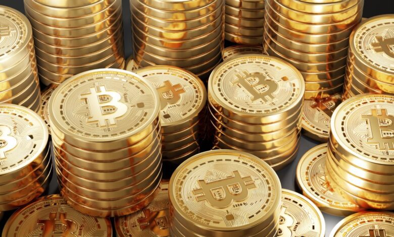 Stacks of shiny gold-colored coins featuring the Bitcoin symbol, representing cryptocurrency wealth or investment.